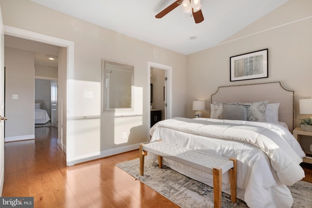 bedroom featuring light wood-type flooring, vaulted ceiling, and ceiling fan