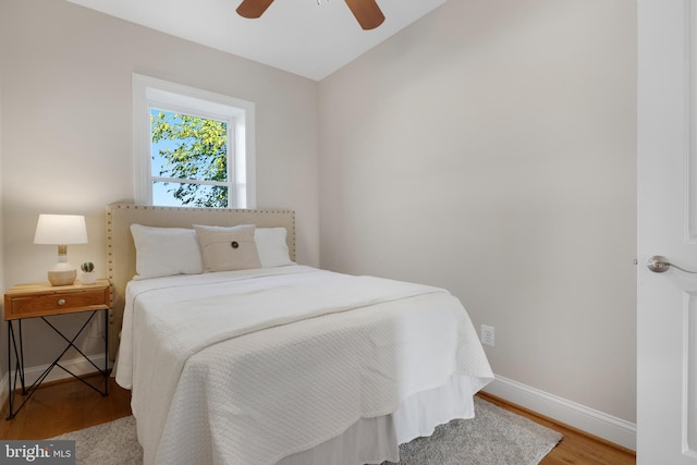 bedroom with ceiling fan, vaulted ceiling, and hardwood / wood-style floors