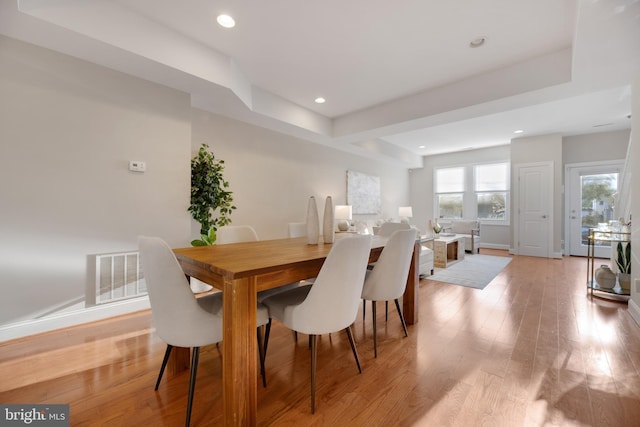 dining area with light wood-type flooring and a tray ceiling