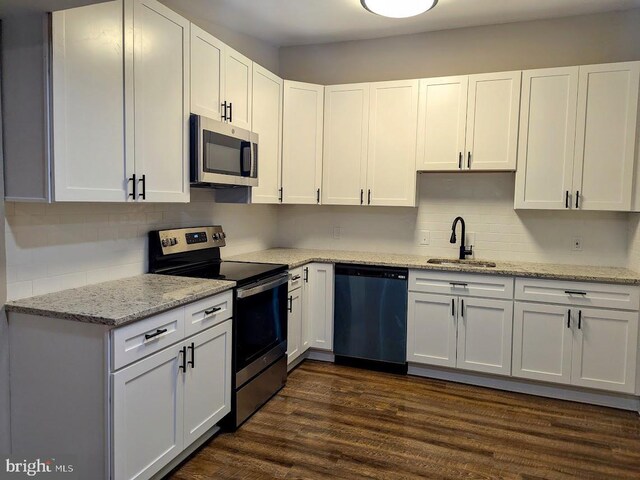 kitchen with light stone countertops, dark hardwood / wood-style flooring, stainless steel appliances, sink, and white cabinets