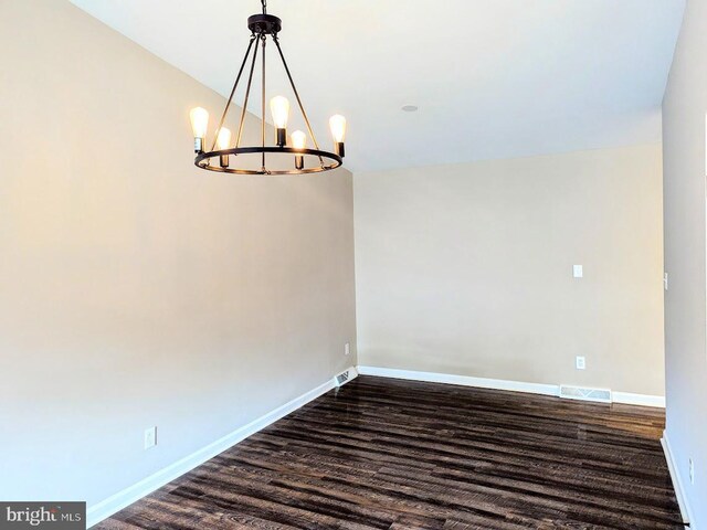 unfurnished room featuring dark wood-type flooring and a chandelier