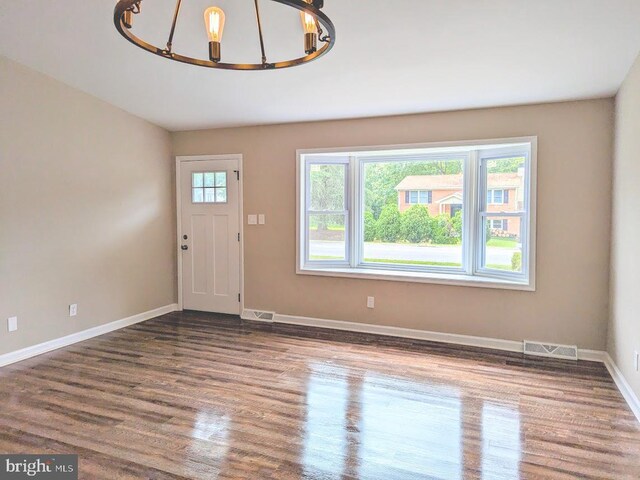 foyer featuring a healthy amount of sunlight, a notable chandelier, and hardwood / wood-style floors