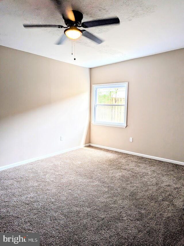 unfurnished room featuring a textured ceiling, carpet flooring, and ceiling fan