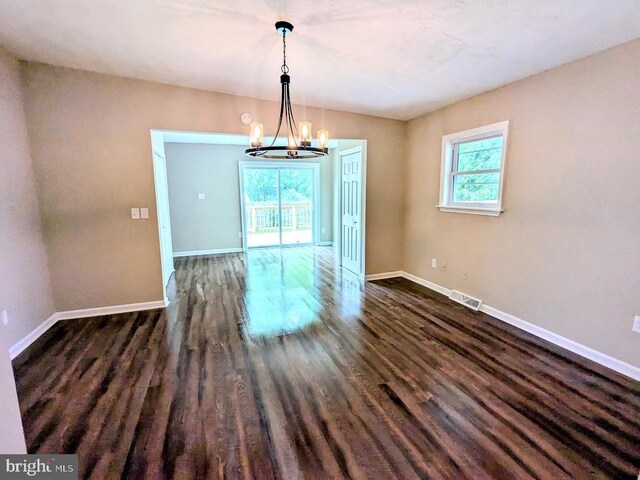 unfurnished dining area with a notable chandelier and dark hardwood / wood-style floors