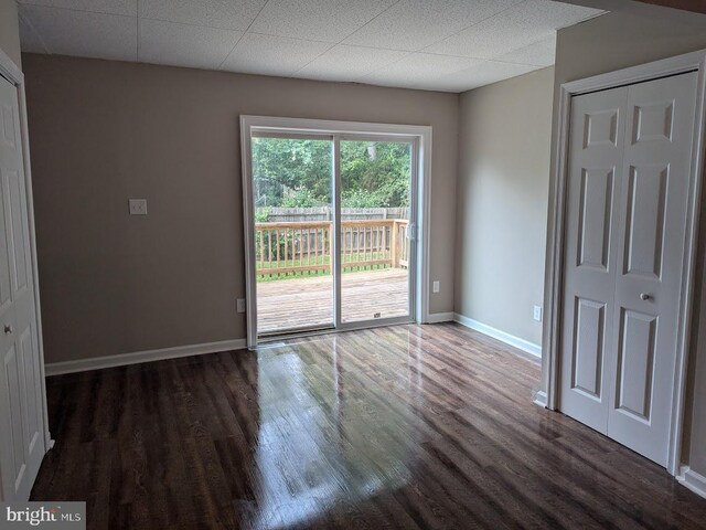 unfurnished room with dark wood-type flooring and a drop ceiling