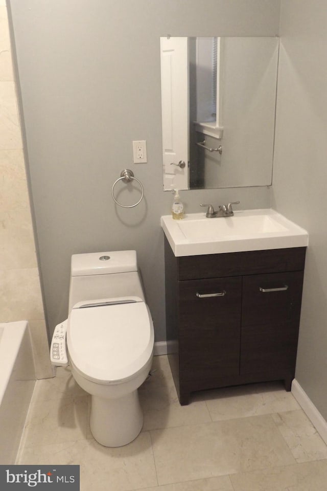 bathroom featuring tile patterned floors, a bathtub, vanity, and toilet