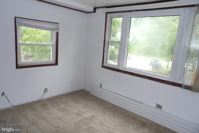 carpeted spare room featuring a baseboard heating unit and a healthy amount of sunlight