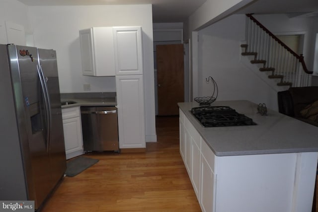 kitchen featuring stainless steel appliances, white cabinetry, and light wood-type flooring