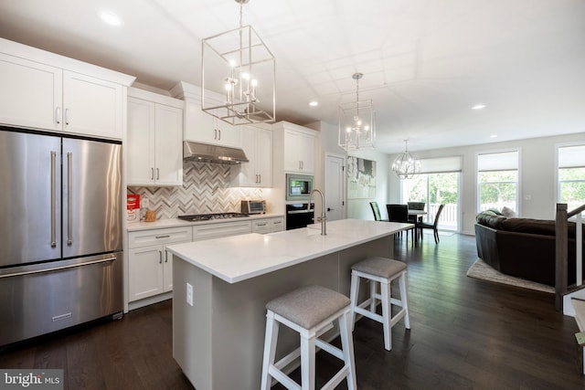 kitchen with white cabinets, pendant lighting, an island with sink, and stainless steel appliances