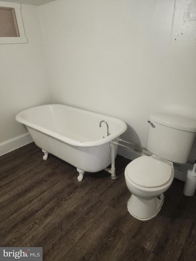 bathroom with a tub, toilet, and hardwood / wood-style flooring