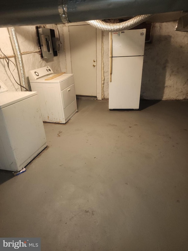 basement with electric panel, washer and clothes dryer, and white refrigerator