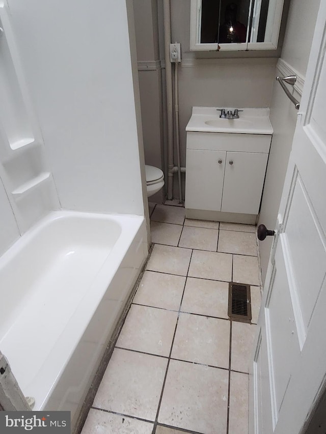 bathroom with tile patterned flooring, vanity, toilet, and a tub