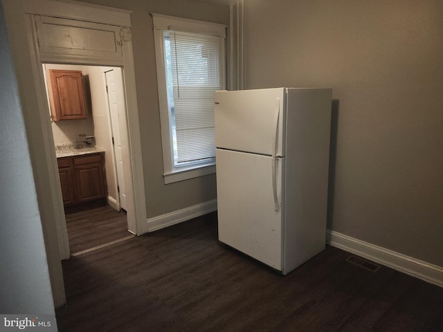 kitchen featuring dark wood-type flooring, a healthy amount of sunlight, and white fridge