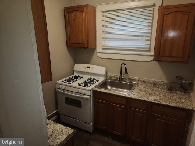 kitchen featuring white gas range oven and sink