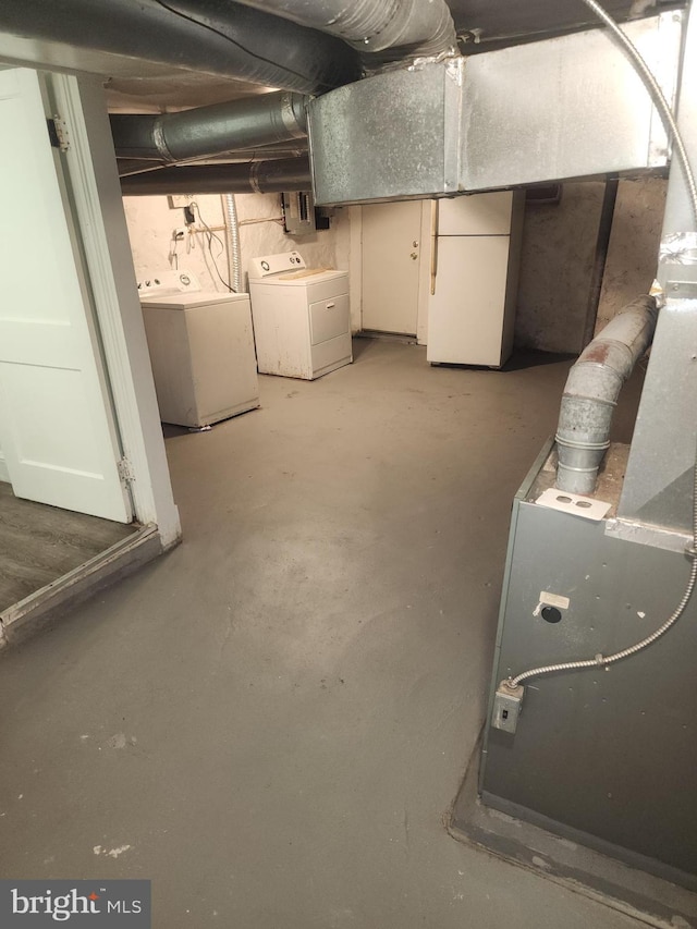 basement featuring washing machine and clothes dryer and white refrigerator