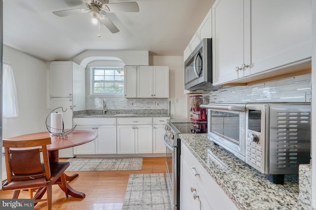 kitchen featuring light wood-type flooring, appliances with stainless steel finishes, white cabinetry, and ceiling fan