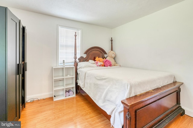 bedroom with a textured ceiling and light hardwood / wood-style flooring