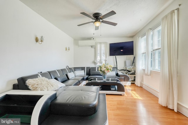 living room with ceiling fan, wood-type flooring, and an AC wall unit