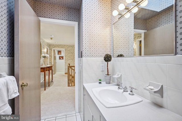 bathroom with tile walls, tile patterned floors, a skylight, and vanity