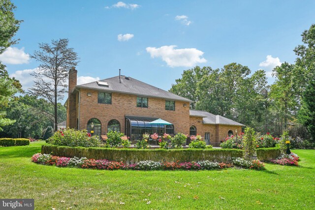 view of front facade with a lawn, a balcony, and french doors