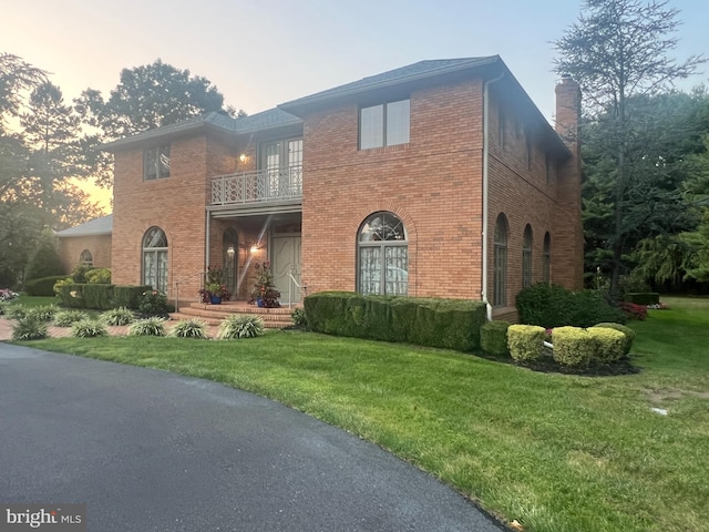 view of front of property with a balcony and a lawn