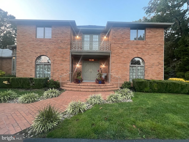 view of front of home with a balcony and a front lawn