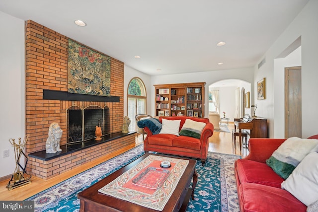 living room with a brick fireplace and wood-type flooring