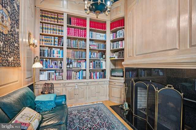 living area with light wood-type flooring, a chandelier, and built in features