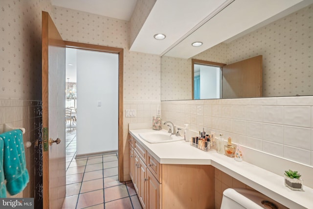 bathroom with tile walls, vanity, toilet, and tile patterned floors