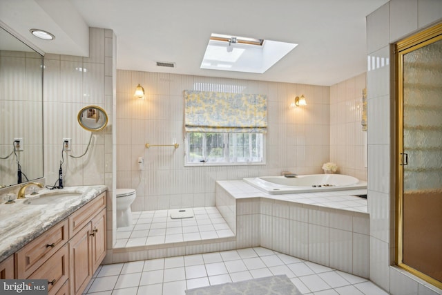 full bathroom featuring tile walls, vanity, plus walk in shower, a skylight, and toilet