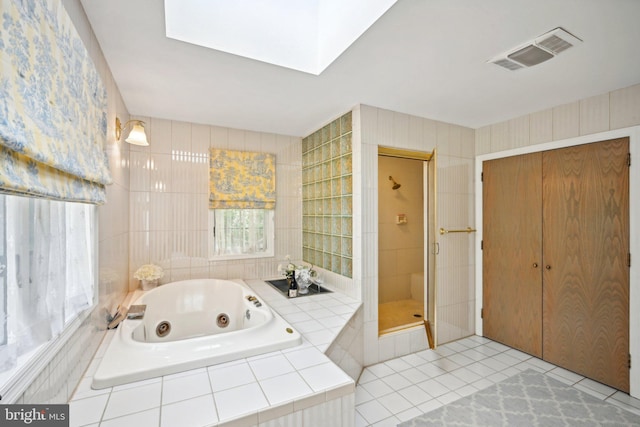 bathroom with shower with separate bathtub, tile patterned flooring, a skylight, and a wealth of natural light