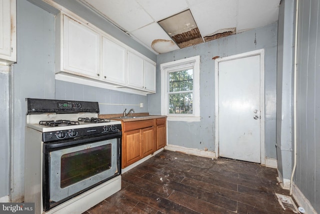 kitchen with dark wood-type flooring, white cabinetry, white gas range oven, and sink