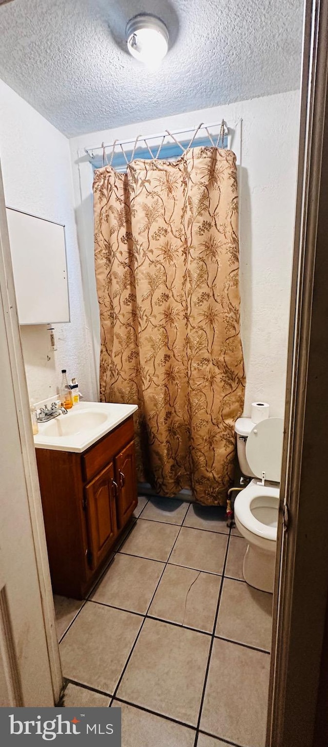 bathroom with vanity, a textured ceiling, toilet, and tile patterned flooring