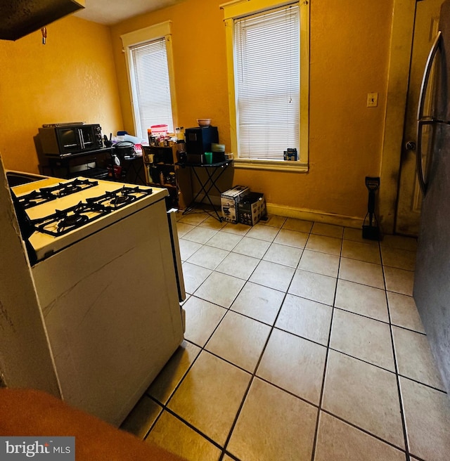 kitchen with white gas stove and light tile patterned flooring