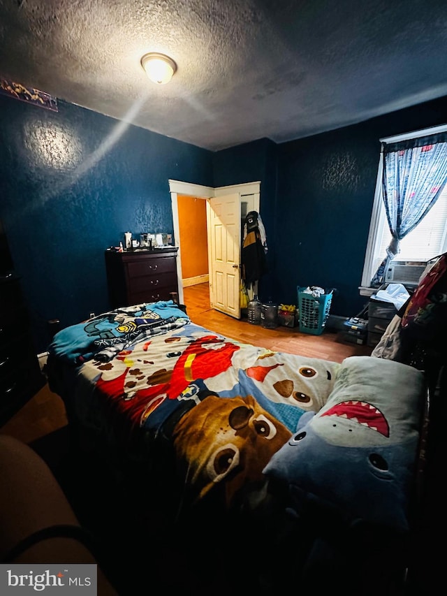 bedroom with a textured ceiling and hardwood / wood-style flooring