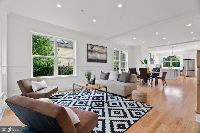 living room featuring a healthy amount of sunlight, light hardwood / wood-style floors, and crown molding