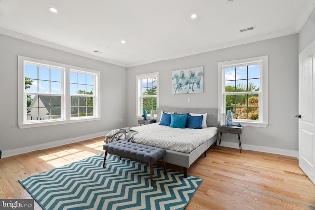 bedroom with ornamental molding and light hardwood / wood-style floors