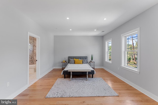 bedroom featuring ensuite bath and light hardwood / wood-style flooring