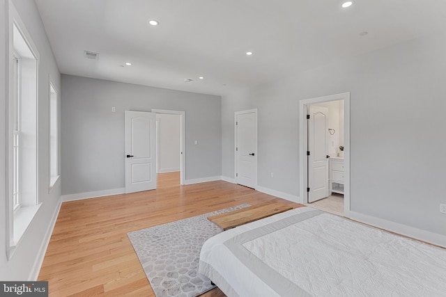 bedroom with light wood-type flooring and ensuite bath