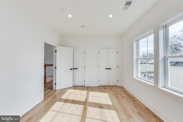 unfurnished bedroom with multiple closets and light hardwood / wood-style flooring