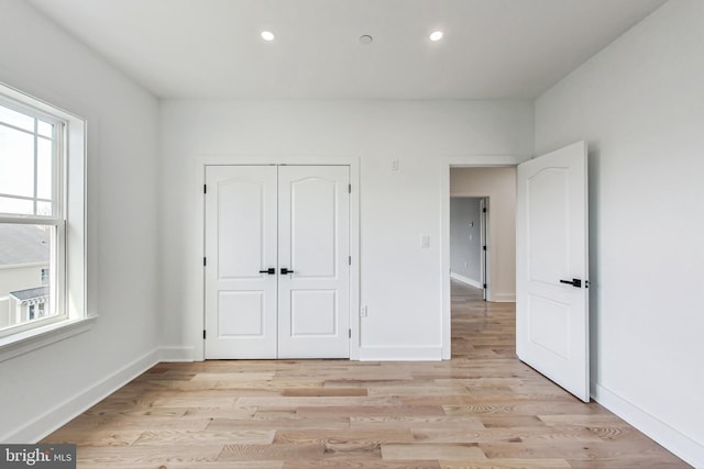 unfurnished bedroom with light hardwood / wood-style flooring and a closet