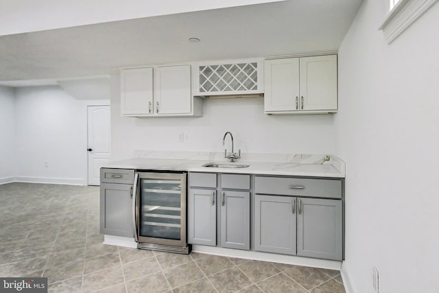 kitchen with gray cabinets, sink, beverage cooler, light tile patterned floors, and light stone countertops