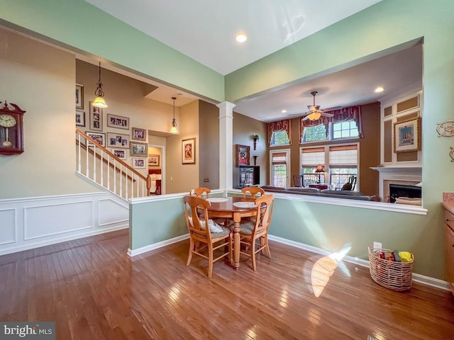 dining space featuring ceiling fan, wood-type flooring, and ornate columns