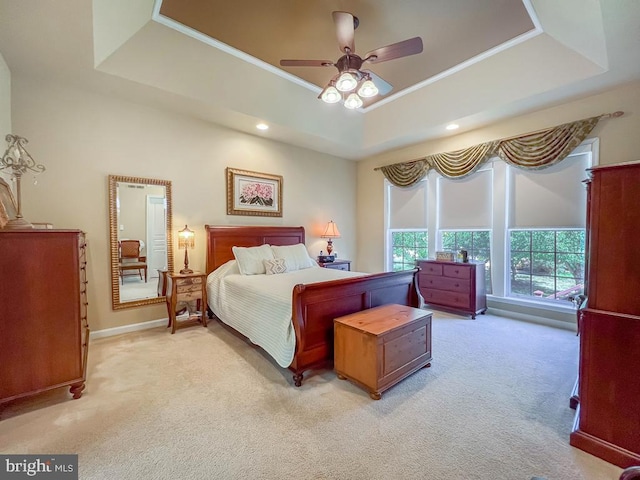 bedroom with light carpet, a raised ceiling, and ceiling fan