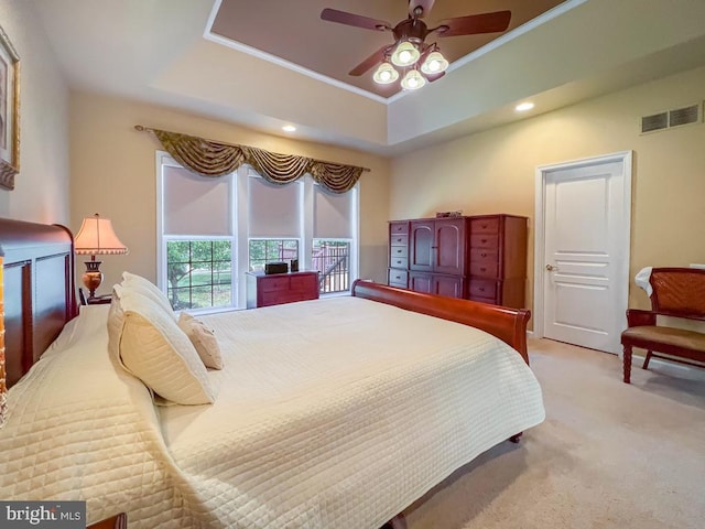 bedroom featuring light carpet, a raised ceiling, and ceiling fan