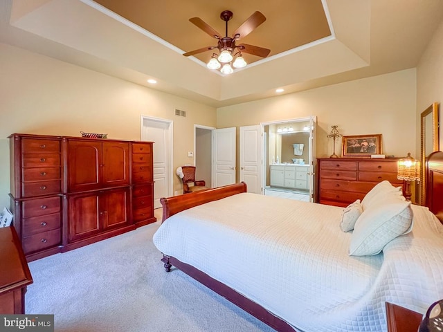 carpeted bedroom with a raised ceiling, ensuite bath, and ceiling fan