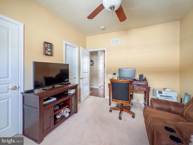 carpeted home office featuring ceiling fan