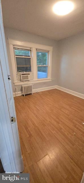 unfurnished room with cooling unit, wood-type flooring, and radiator