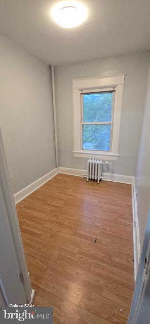 unfurnished room featuring radiator heating unit and hardwood / wood-style floors