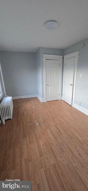 unfurnished bedroom featuring radiator heating unit and hardwood / wood-style flooring